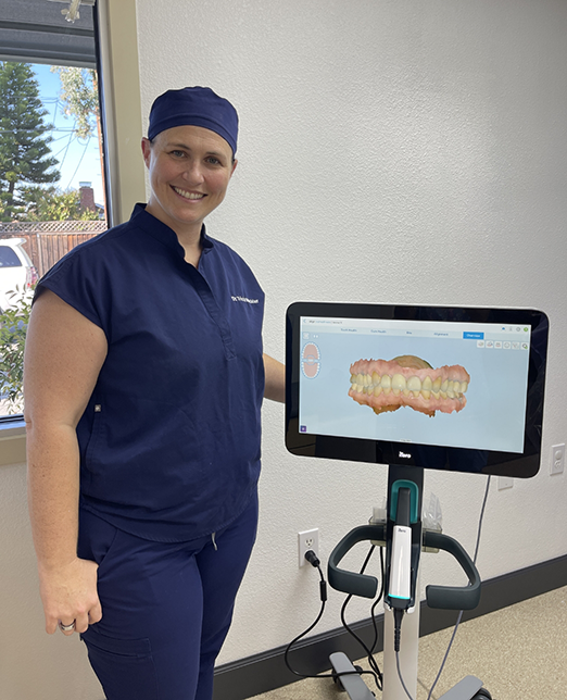 Dental team member standing next to monitor showing teeth