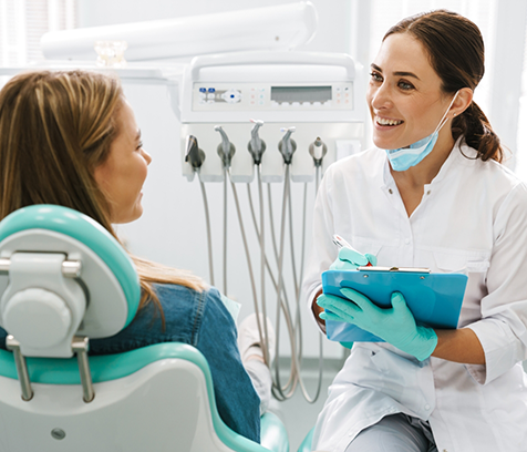 Dentist with clipboard talking to patient