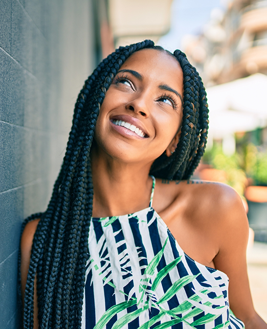 Woman with long hair smiling and leaning against a wall