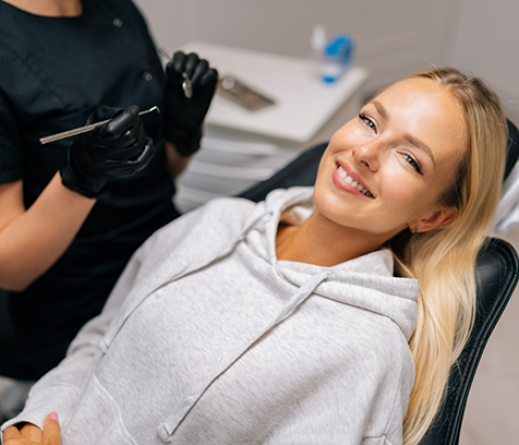 Female patient leaning back in dental chair and smiling