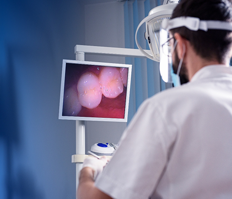 Dentist using intraoral camera to look at teeth on monitor