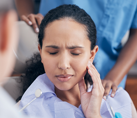 Close-up of woman rubbing her jaw in pain