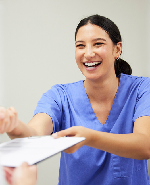 Dentist in blue shirt handing form to offscreen patient