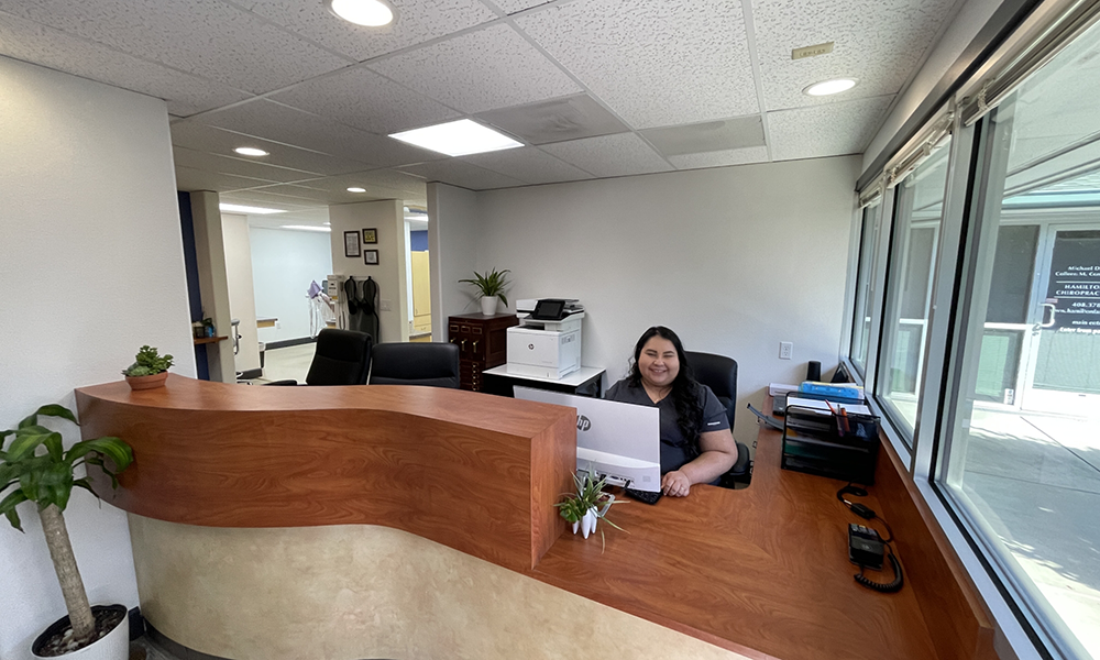 Dental team member sitting at large wooden front desk