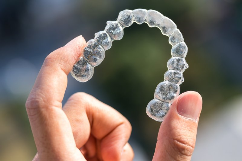 up-close view of hand holding Invisalign aligner